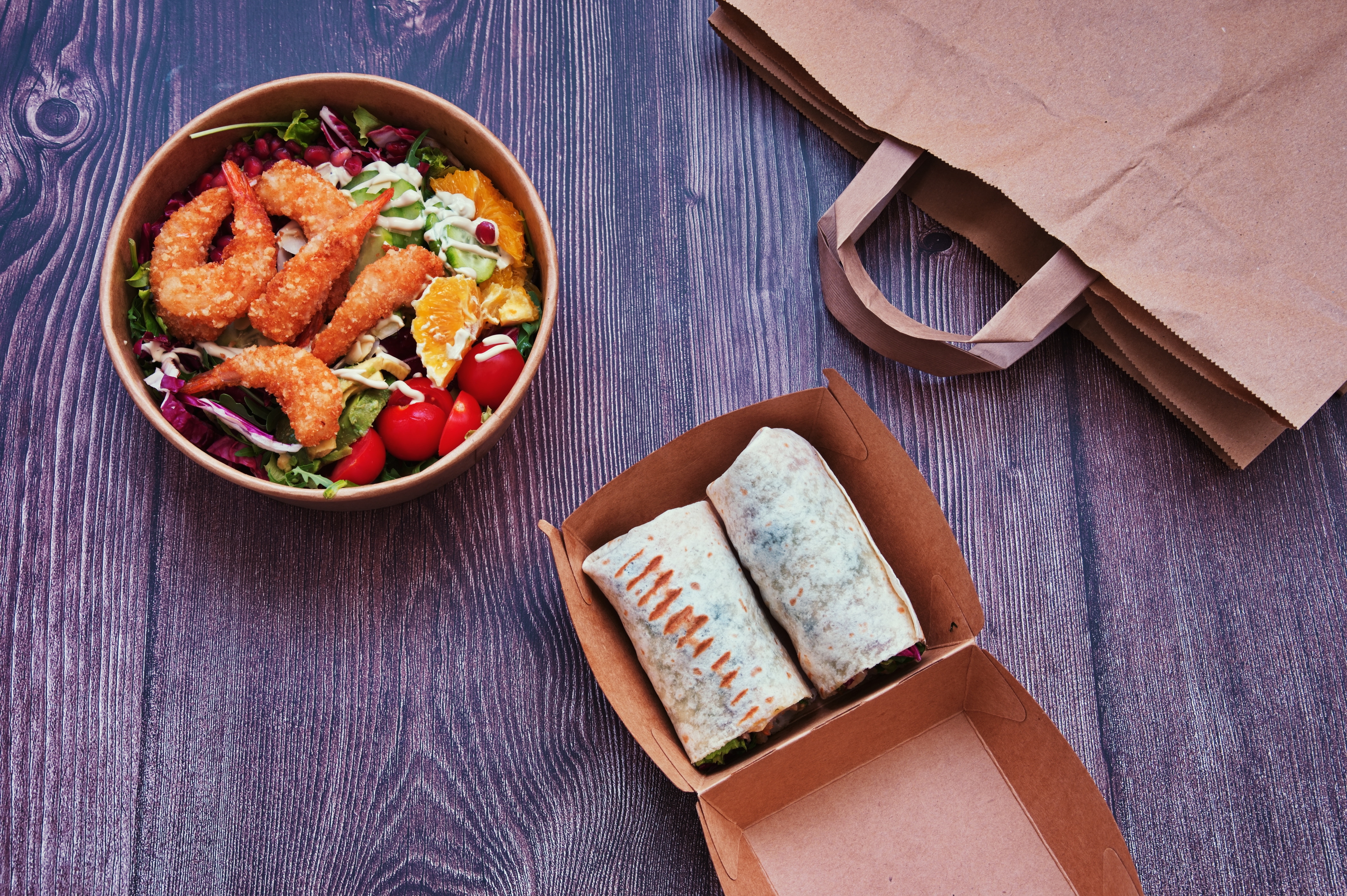 Ensalada fresca, pollo a la plancha y frutas en envases biodegradables listos para llevar, comida saludable para llevar sobre una mesa