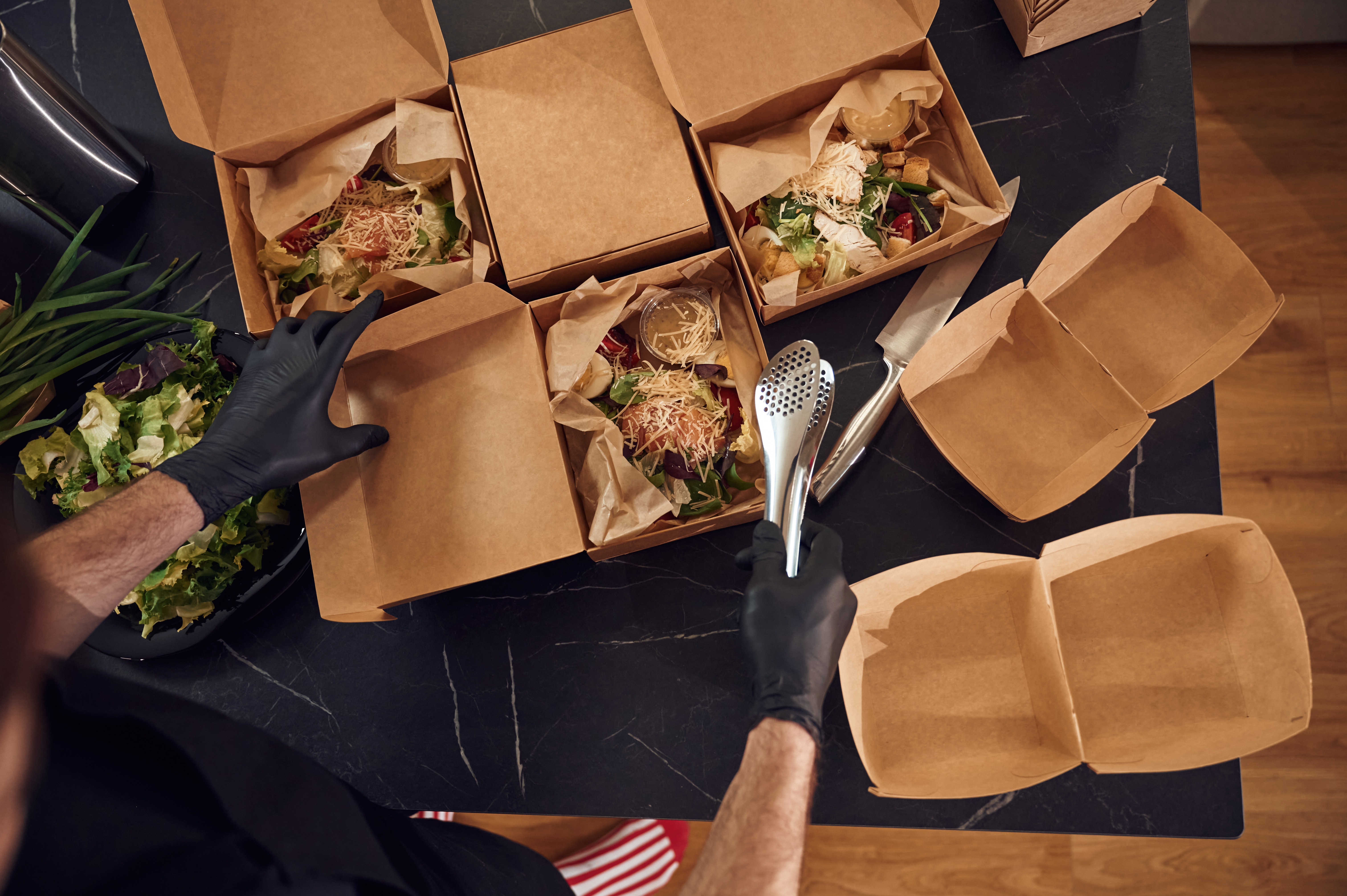 Persona revisando pedido de comida para llevar en casa, comprobando envases y lista de platos para evitar errores comunes